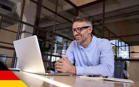 Man with glasses smiling in front of laptop