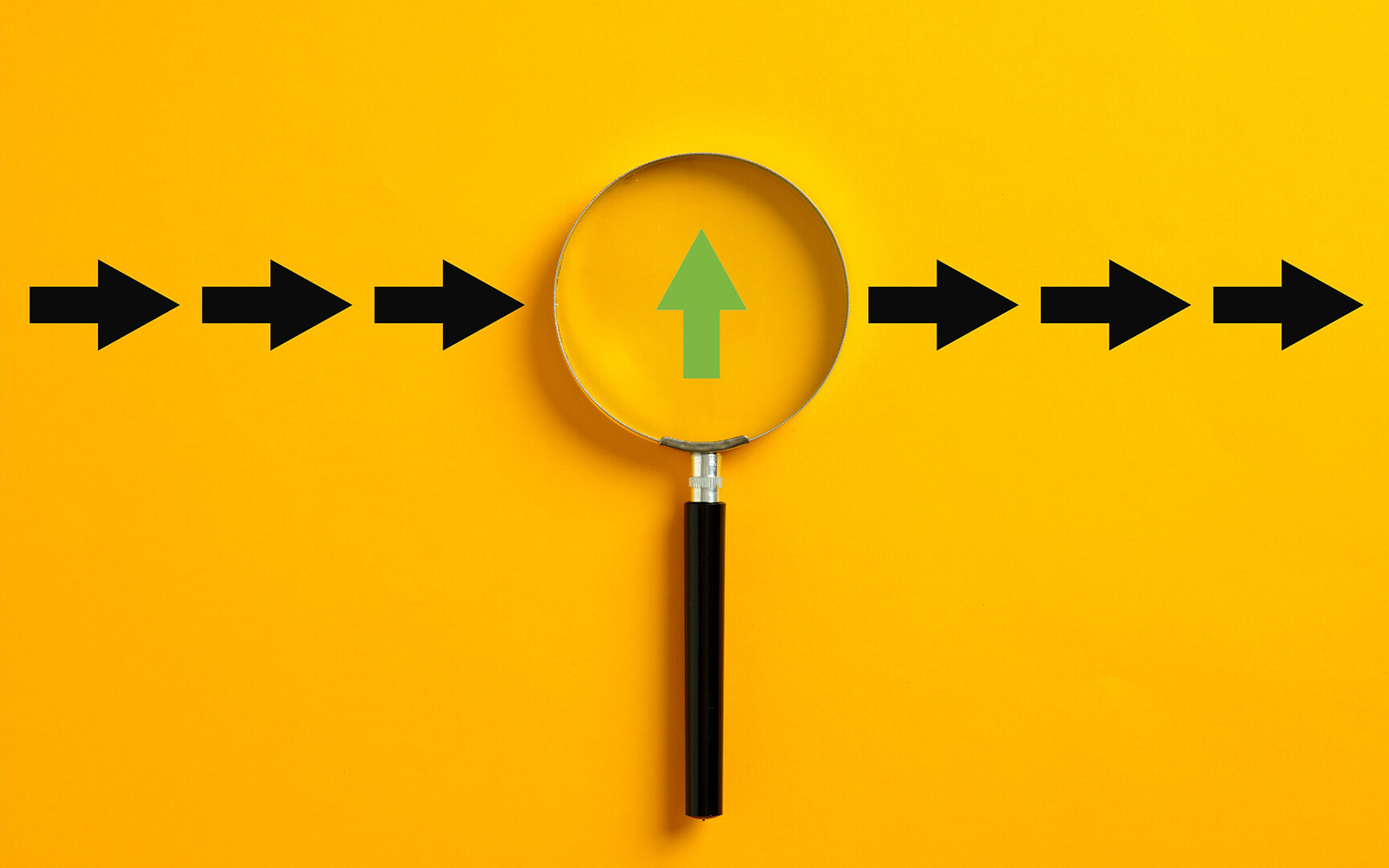 A magnifying glass with a black handle centered over a yellow background, showing a green upward arrow with black arrows pointing right.