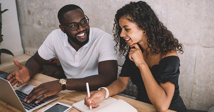 Two individuals collaborate at a table in a professional setting. 