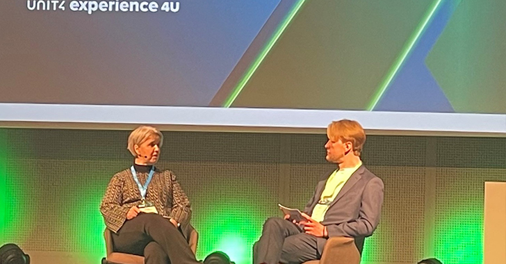 Two speakers seated on stage at a professional event, engaged in a discussion. 