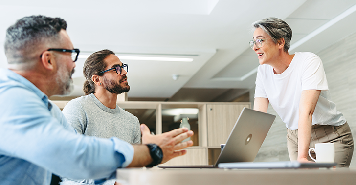 Three people in a modern office setting engaged in a discussion