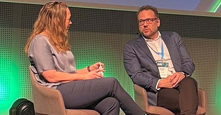 Two professionals seated in modern armchairs on a stage, engaged in a panel discussion.