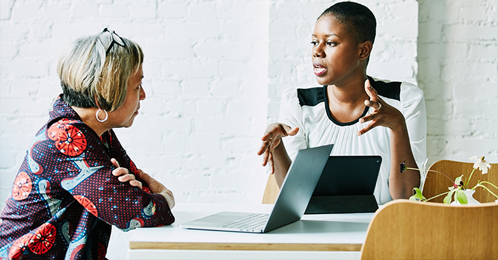 Two women seated at a modern table in a professional setting. 