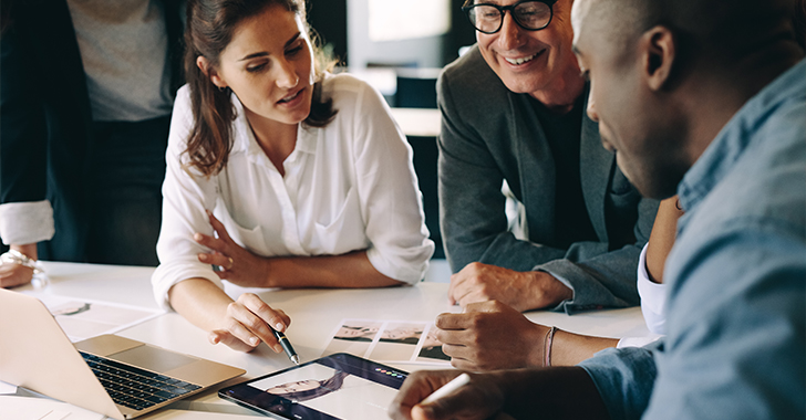 Four professionals collaborating around a white table in a modern office setting. 