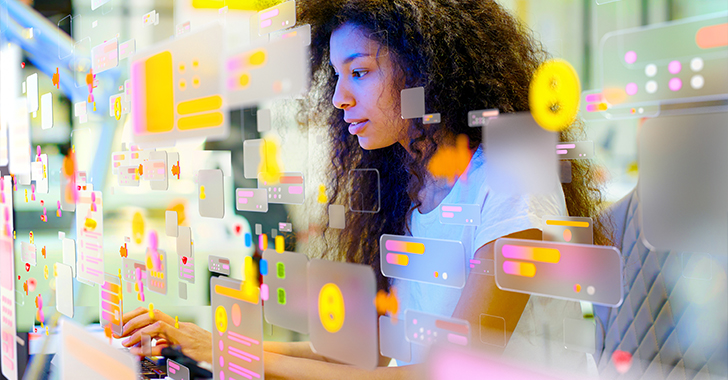 A person with curly hair sits at a desk, intently focused on a computer screen.