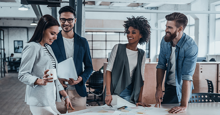 Four colleagues gathered around a table in a modern office, engaged in a collaborative discussion. 