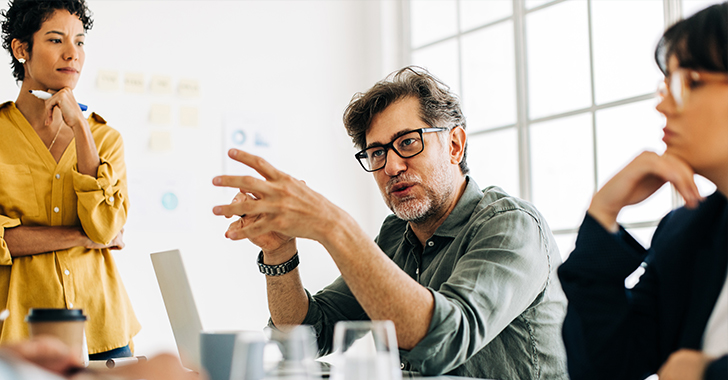 Three professionals in a modern office engage in a collaborative discussion. 