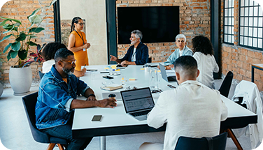 A modern office meeting with eight professionals around a sleek conference table.