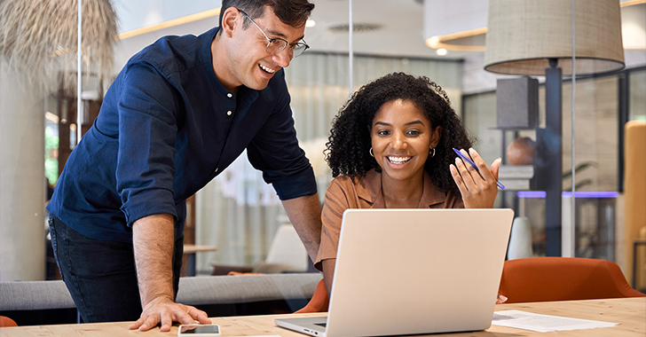 A man and a woman collaborate at a wooden table in a modern office