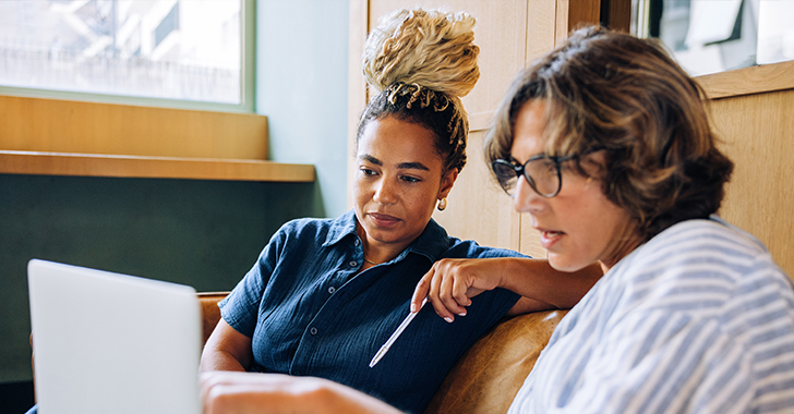 Two women collaborate in a cozy, well-lit indoor setting. 