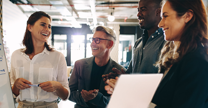 Four diverse professionals collaborate in a bright, modern office.