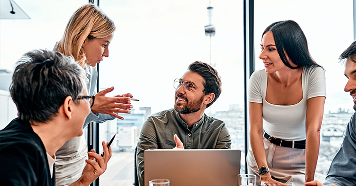 Five professionals collaborate around a light-colored table in a modern office. 