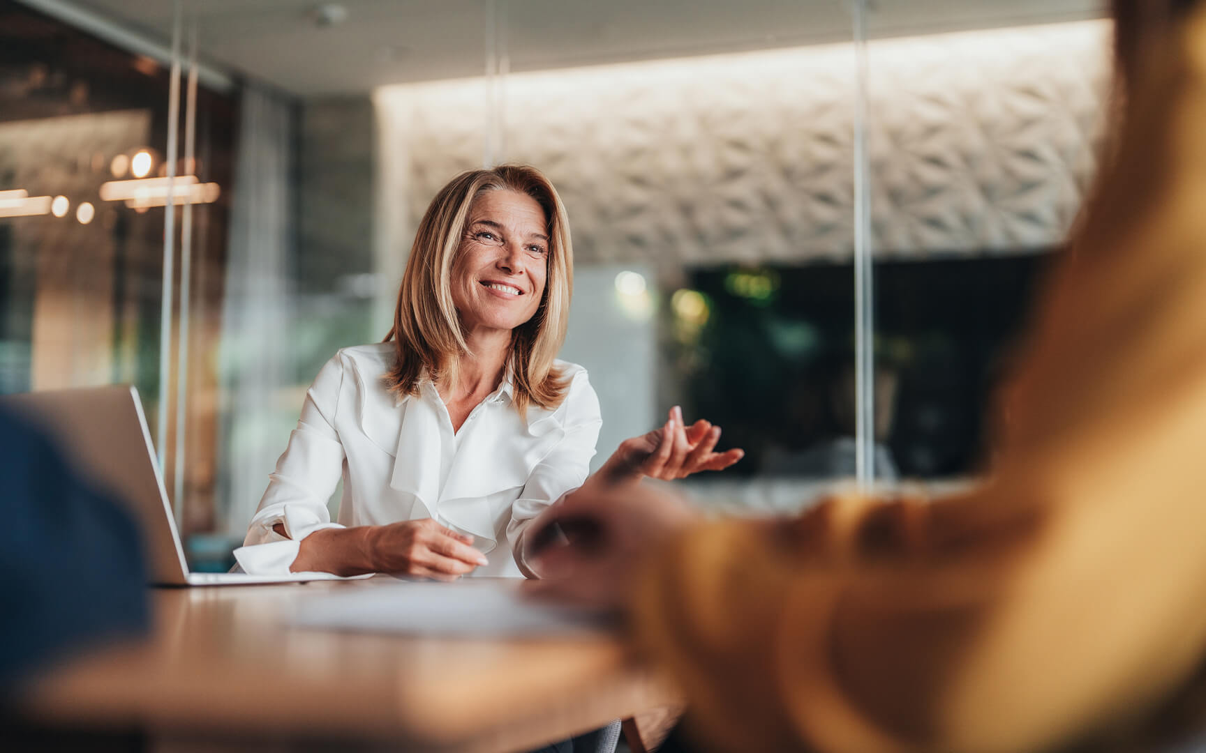 Person in a meeting across a desk, discussing onboarding or HR processes in an office setting, representing human-led employee support and engagement.