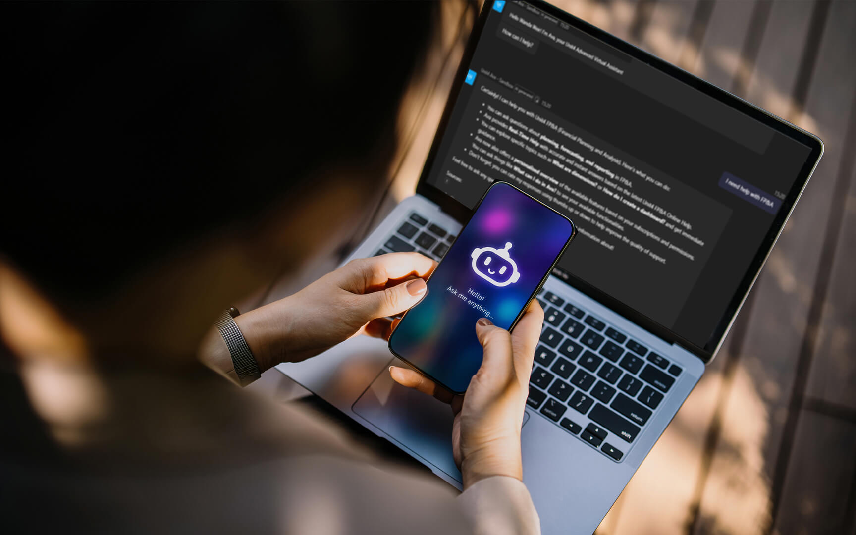 Person using a smartphone with an AI assistant while working on a laptop showing FP&A data, illustrating real-time finance support and productivity.