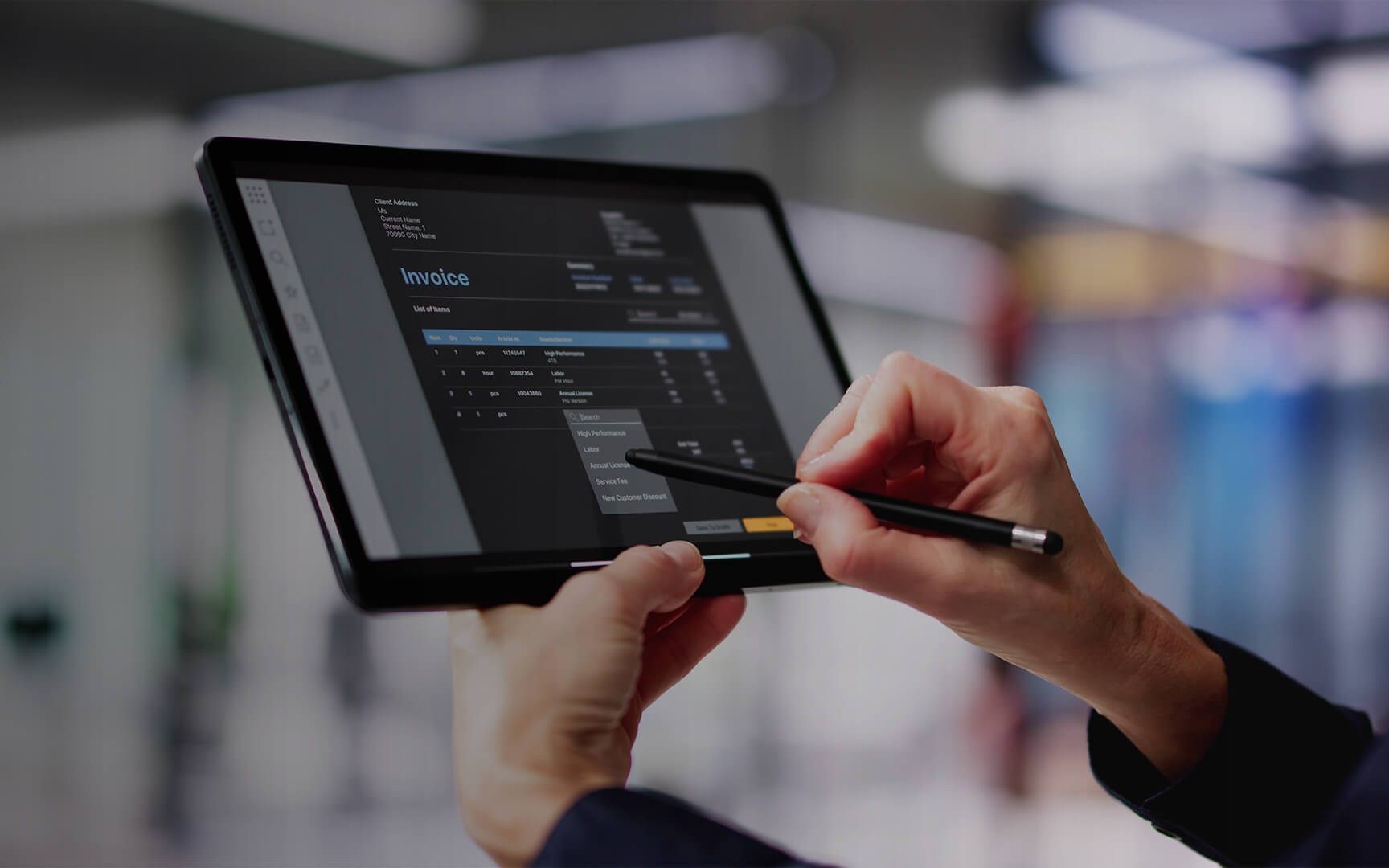 Professional using a tablet to review and edit an invoice in a digital finance application.