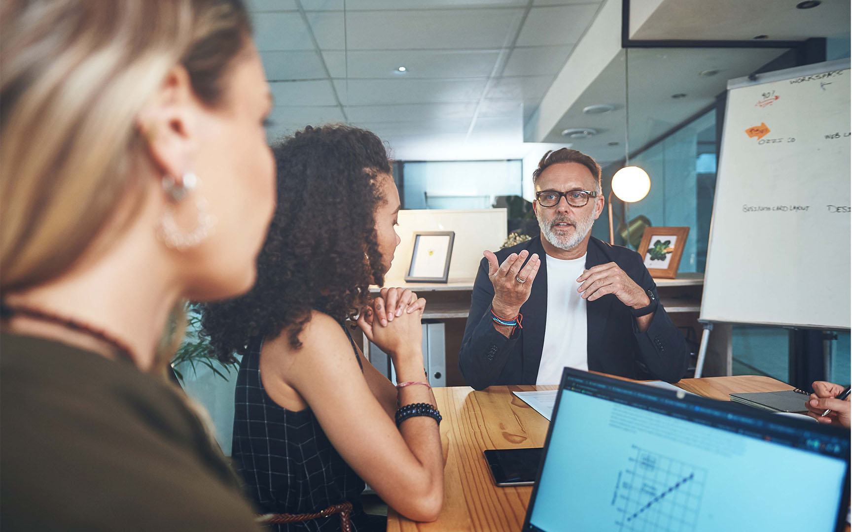 Business professionals collaborating in a modern meeting room, with one participant presenting ideas during a strategic sourcing or procurement discussion while colleagues listen around a conference table.