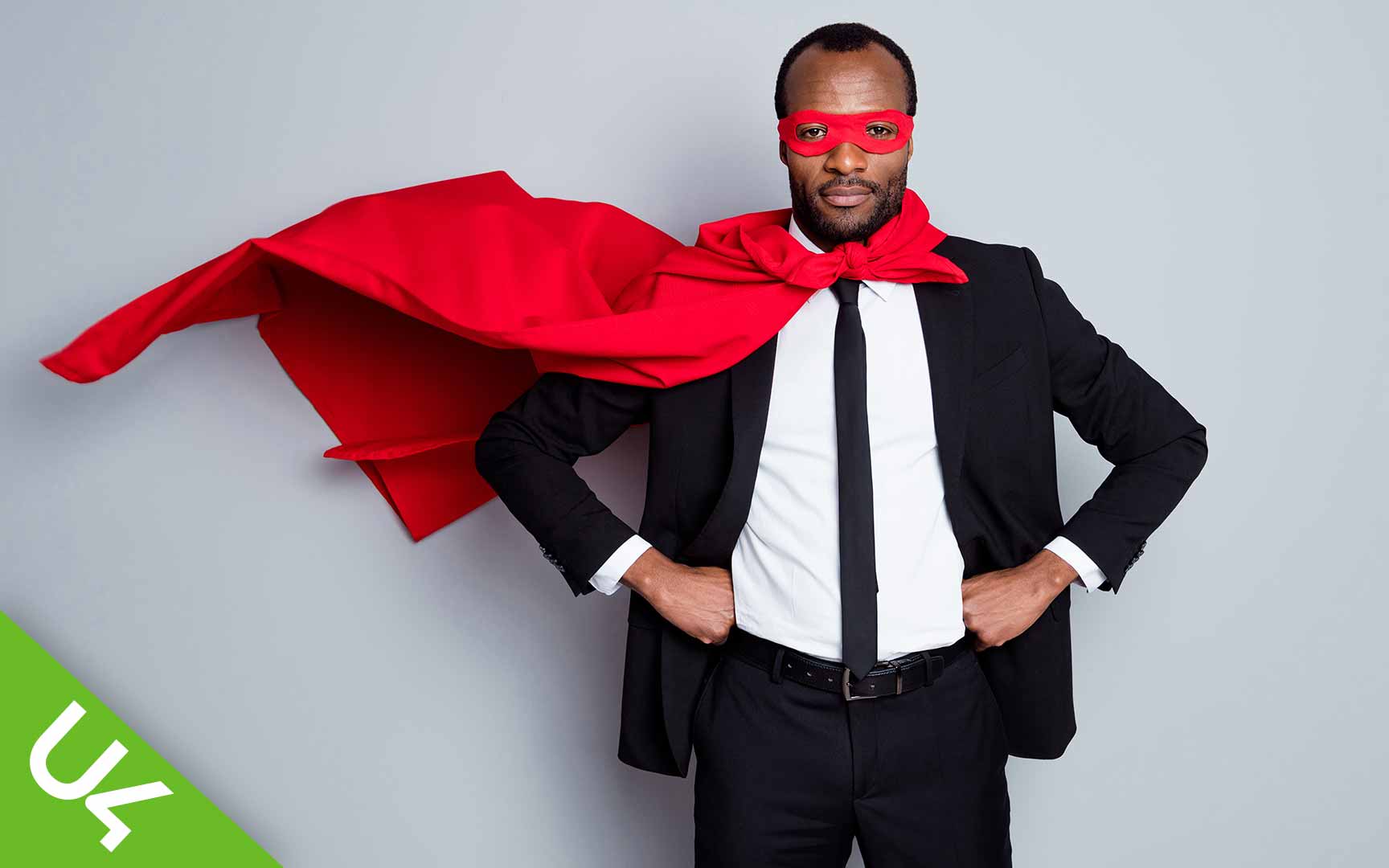 Mies puvussa päällään supersankarin viitta ja naamio