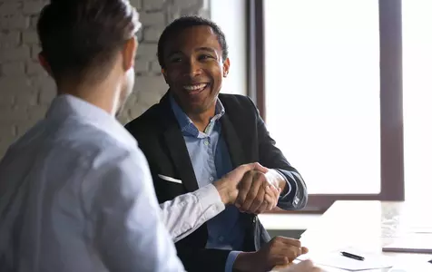 Two men shaking hands with a contract on the table