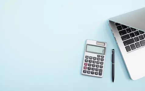A laptop and calculator on a light blue background