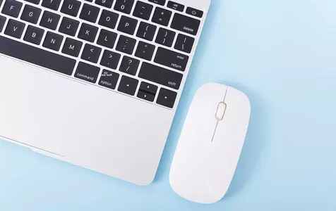 A laptop with a modern white mouse on a light blue background