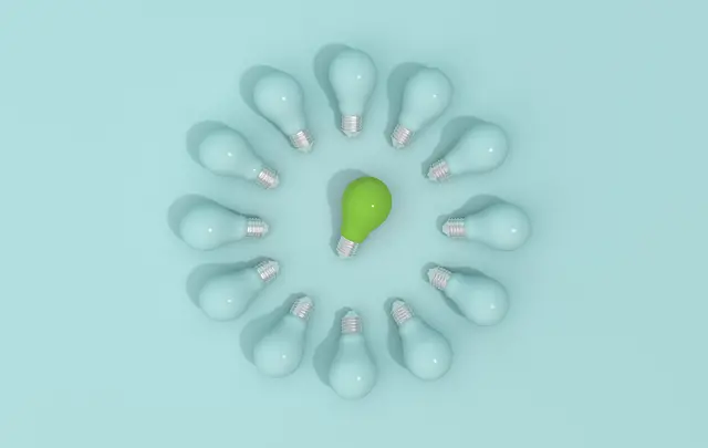 A circle of light bulbs with one green bulb in the center among blue ones