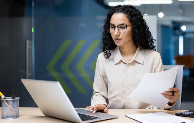 woman sited at a table looking at a laptop