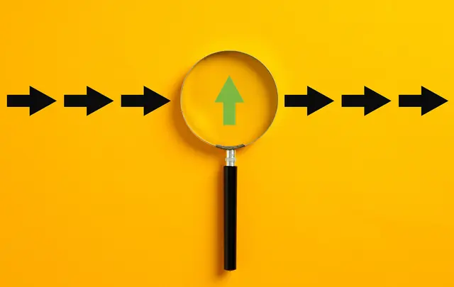 A magnifying glass with a black handle centered over a yellow background, showing a green upward arrow with black arrows pointing right.