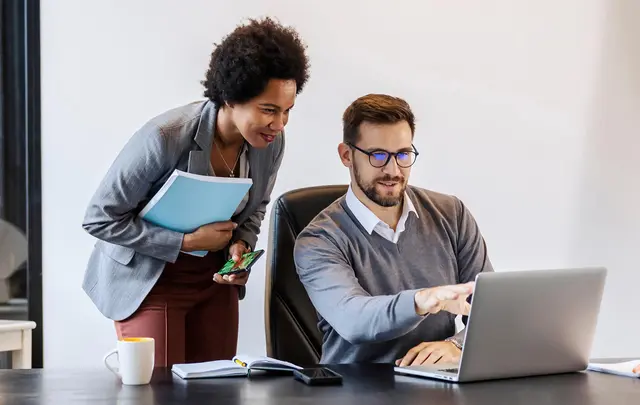 couple talking while pointing to a laptop
