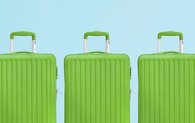 Three green hard-shell suitcases lined up against a light blue background