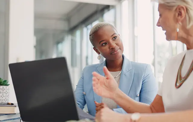 Two individuals in a modern office setting engaged in a professional discussion