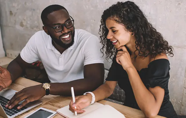 Two individuals collaborate at a table in a professional setting. 