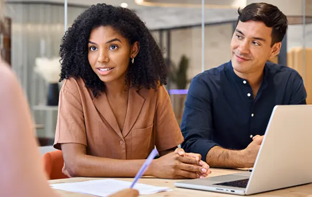 Three individuals in a modern office setting engaged in a professional discussion. 