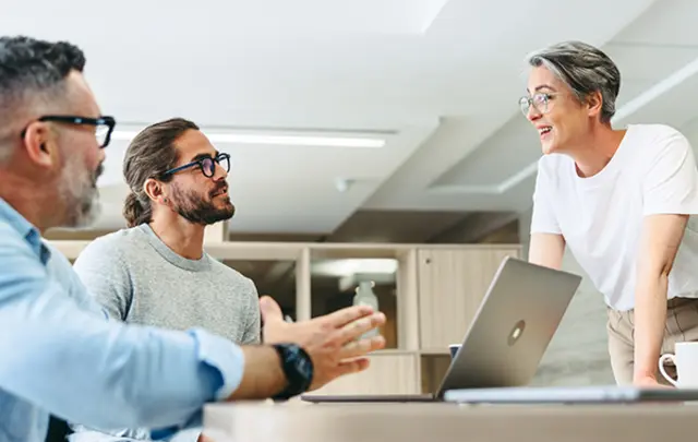 Three people in a modern office setting engaged in a discussion