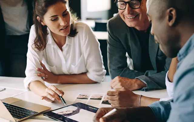 Four professionals collaborating around a white table in a modern office setting. 