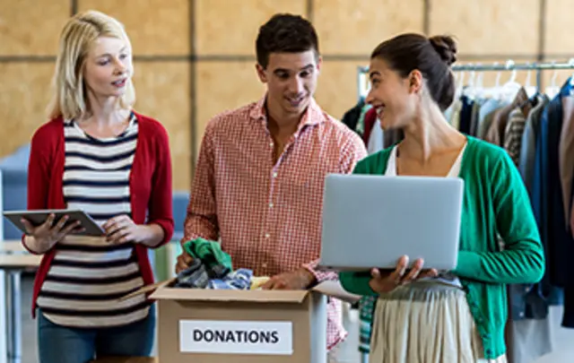 three people gather around a box labeled "donations"