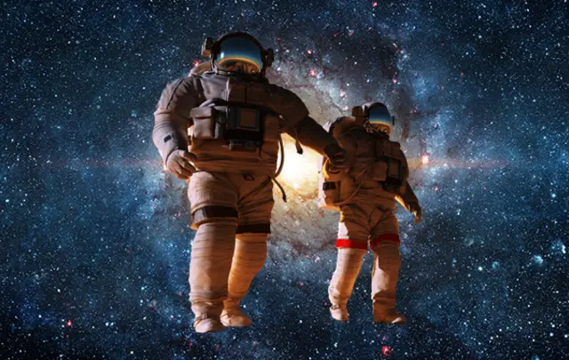 Two astronauts, one larger and one smaller, hold hands while floating in the vastness of space. 