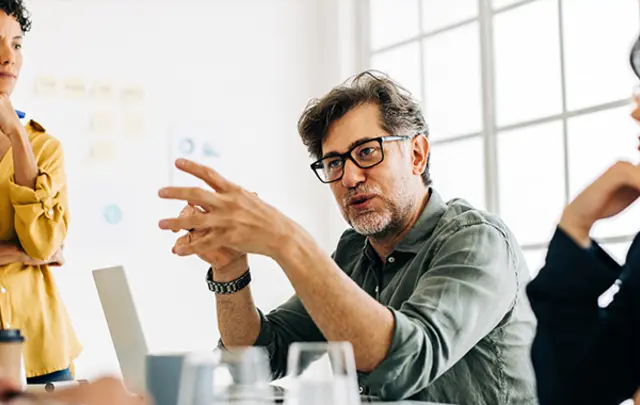Three professionals in a modern office engage in a collaborative discussion. 
