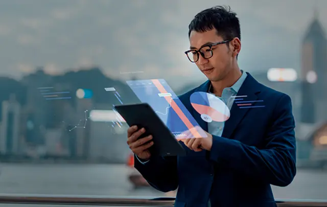 An Asian man in a dark blue suit interacts with a holographic display projected from a tablet.