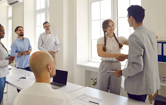 Three professionals collaborate around a light-colored desk in a modern office. 
