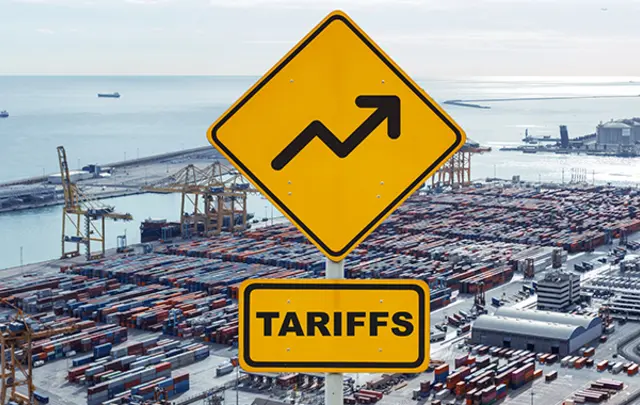 Two bright yellow road signs in the foreground, one featuring an upward-trending arrow and the other labeled 'TARIFFS,' set against an aerial view of a bustling shipping port. 