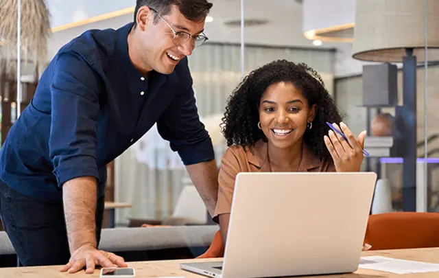 A man and a woman collaborate at a wooden table in a modern office