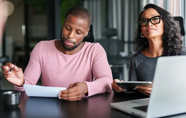 A professional setting with two colleagues at a dark table.