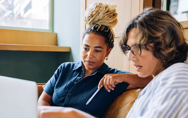 Two women collaborate in a cozy, well-lit indoor setting. 