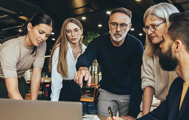 Five professionals collaborate around a table in a modern office.