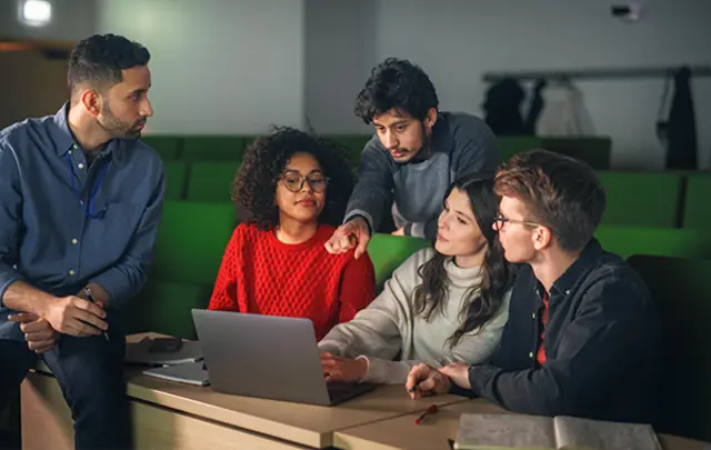 Five students collaborate in a university lecture hall. 