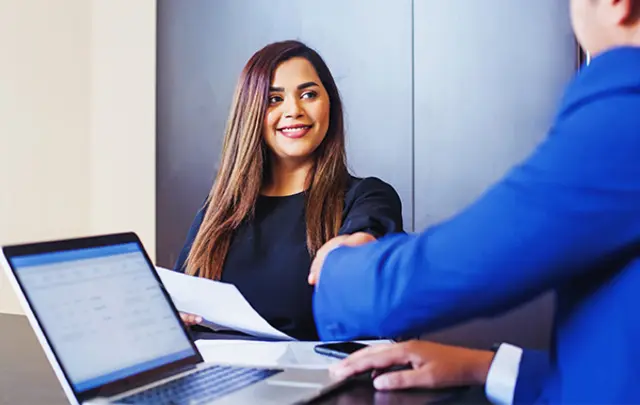 A professional handshake between two individuals in an office setting