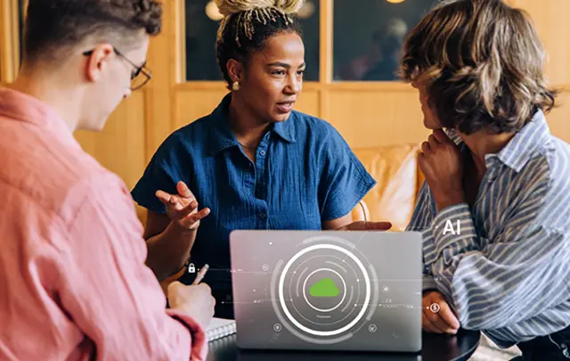 Three colleagues collaborate around a laptop in a warm, modern workspace.