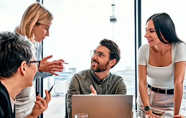Five professionals collaborate around a light-colored table in a modern office. 