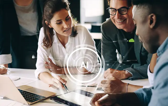 A group of four professionals collaborating around a laptop with AI graphics displayed on a tablet. 