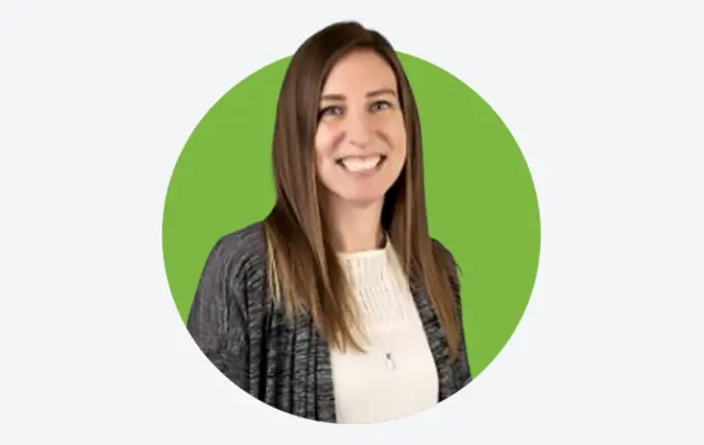 Professional portrait of a woman wearing a light top and dark cardigan, standing against a green circular background.